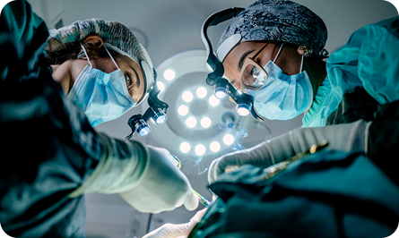 Equipo médico con mascarillas y gorros quirúrgicos operando bajo las luces de un pabellón