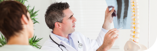 Traumatólogo en consulta revisando radiografia de de columna vertebral