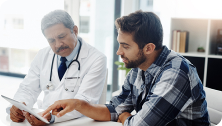Médico explicando a su paciente sobre el cáncer en consulta oncológica.