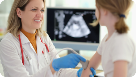 Traumatóloga infantil realizando ecotomografia de codo a una niña