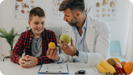 Nutriólogo infantil educando a paciente pediátrico sobre la importancia de comer frutas